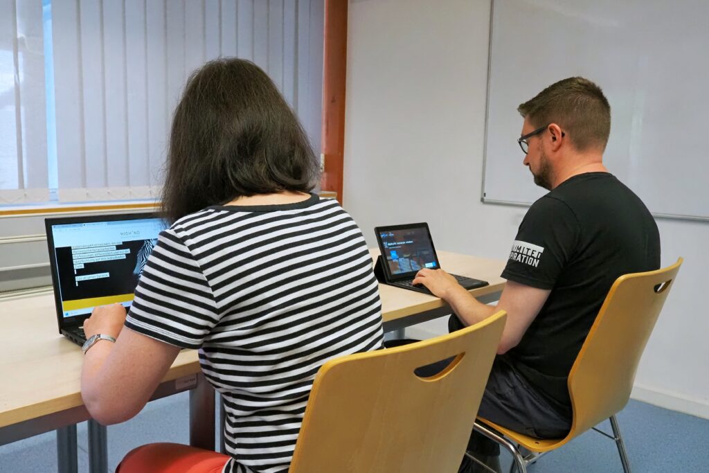 Zwei Personen sitzen an Notebooks